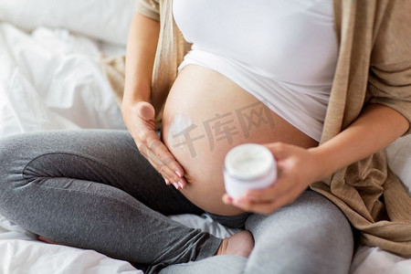 怀孕、人和生育概念-孕妇在腹部涂抹妊娠纹霜的特写。孕妇美女