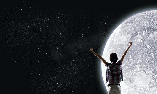 女孩仰望天空摄影照片_满月。举起双手仰望天空中月亮的年轻女子的背影