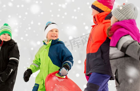 一群小孩子摄影照片_童年，雪橇和季节概念—一群快乐的小孩子在冬天雪橇。快乐的小孩子与雪橇在冬天