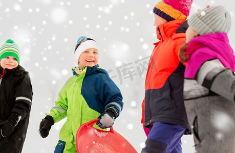 童年，雪橇和季节概念—一群快乐的小孩子在冬天雪橇。快乐的小孩子与雪橇在冬天