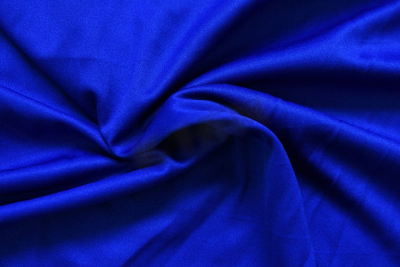 蓝色布纹摄影照片_抽象深蓝色皱巴巴的织物纹理背景/光滑优雅的蓝色丝绸，缎子豪华布波浪