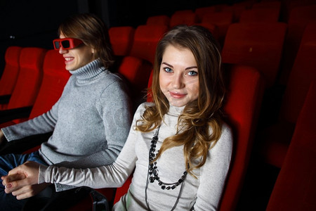 坐在车里看电影摄影照片_年轻夫妇坐在电影院里看电影
