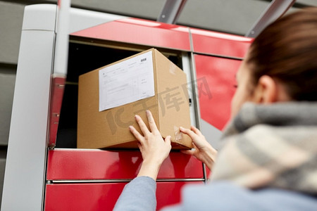 邮件投递和邮政服务概念-女性投递箱到自动包裹机。一位女士把箱子放到自动包裹取款机上