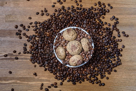 白色盘子里的咖啡饼干，咖啡豆放在棕色的木桌上