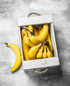 新鲜香蕉放在木箱里。在白色乡村背景。新鲜香蕉放在木箱里。