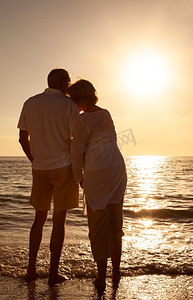 浪漫的高级男人和女人夫妇手拥抱在日落或日出在一个废弃的热带海滩