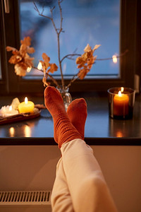 万圣节，hygge和休闲概念—脚在袜子在家里窗台在秋天。脚在袜子在窗台上在秋天