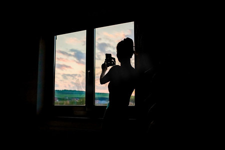 妇女剪影观看日落从窗口隔离概念