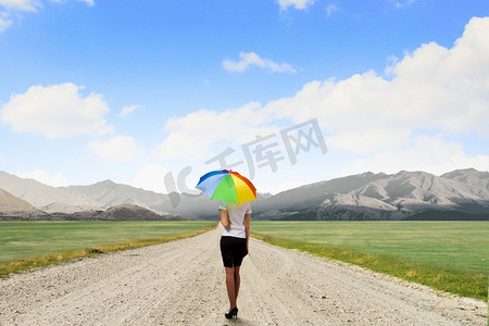 撑着伞的女商人。穿着西装、撑着五颜六色雨伞的女商人的背影