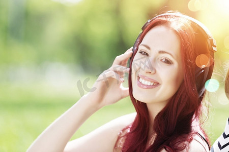 天籁之音。年轻漂亮的女人享受音乐耳机在夏季公园