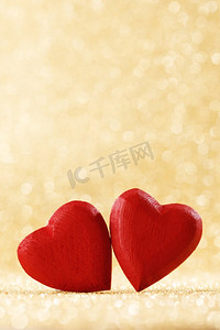 两个红色手工木心在金色明亮的闪光灯bokeh背景。红色的心在闪光背景