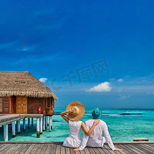 夫妇在白色的热带海滩码头附近的水别墅在马尔代夫