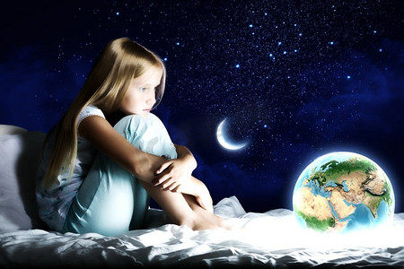 晚安海报星空摄影照片_晚安。女孩坐在床上做梦。这张图片的要素由美国宇航局提供