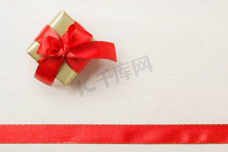 礼品边框摄影照片_假期，现在的概念。小金盒，礼品系装饰蝴蝶结，红丝带边框