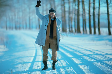 穿着大衣/冬装的时尚男士，在冬日风景的映衬下行走，雪天，暖和的衣服