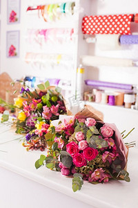 精美花卉装饰摄影照片_在花店的桌子上摆放完了花束。桌上摆放着精美的花束
