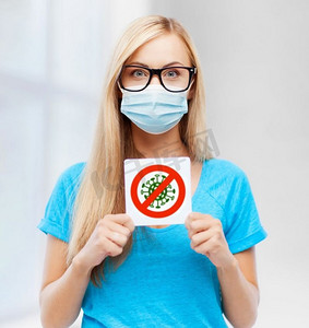 健康、病毒和流行病概念—戴防护口罩的年轻女子手持冠状病毒标志。戴口罩的女子手持冠状病毒标志