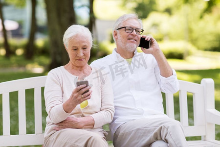 老年、科技和人的概念快乐的老年夫妇在夏季公园拿着智能手机。快乐的高年级夫妇在公园里拿着智能手机