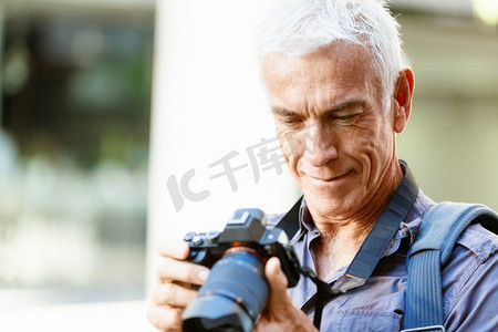 拿着照片摄影照片_在城市里拿着相机的老年男子。寻找好的萌芽
