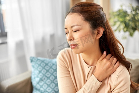 人，健康和问题概念—疲惫的亚洲妇女在家里遭受颈部疼痛。亚洲妇女遭受疼痛在脖子在家里