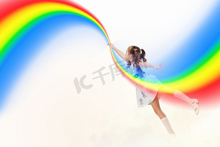 彩虹儿童摄影照片_画彩虹的小女孩。小姑娘用手指画彩虹的形象