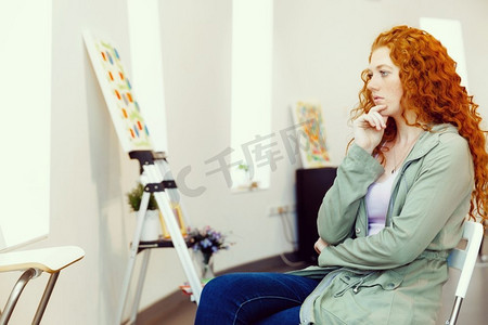 年轻的高加索女子在画廊的画作前。一名年轻的高加索女子在一家美术馆的白色墙上展示的画作前