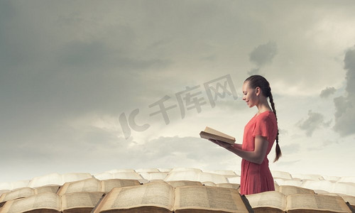 拿着书的女孩。年轻动情的女人穿着红色连衣裙，手里拿着书