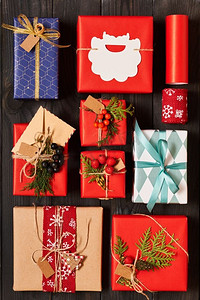 创造性地包装和装饰圣诞节礼物在箱子在黑暗的木背景顶视图从上面.平放。 