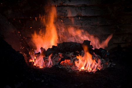 热内摄影照片_传统的铁匠炉燃烧火焰在锻造，车间的炉内燃烧.铁匠设备概念