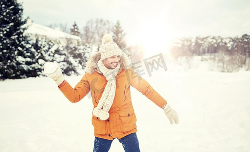人、季节、休闲理念--快乐的年轻人在冬天打雪球。快乐的年轻人在冬天打雪球