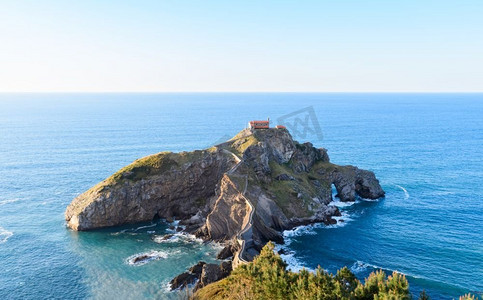 悬崖桥摄影照片_San Juan de Gaztelugatxe，它的中世纪楼梯和桥在日落，巴斯克国家，西班牙。圣胡安德加斯特卢加茨