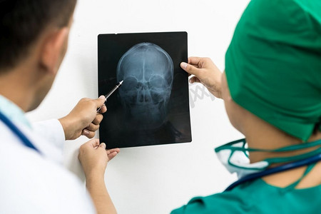 x光头骨摄影照片_医生和外科医生检查病人头部的x光片以检查脑部、颅骨或眼睛损伤。’医学诊断和外科治疗概念。 