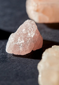 神秘科学和矿物学概念—玫瑰石英晶体和宝石石在石板背景。未加工的玫瑰石英晶体在黑色石板背景