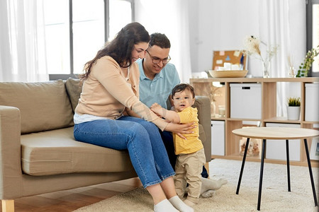 家庭和人的概念—快乐的母亲，父亲和婴儿儿子坐在沙发上在家里。快乐的家庭与孩子坐在沙发上在家里