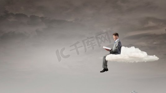 阅读免费摄影照片_男人在孤独中阅读。年轻的商人坐在云上看书