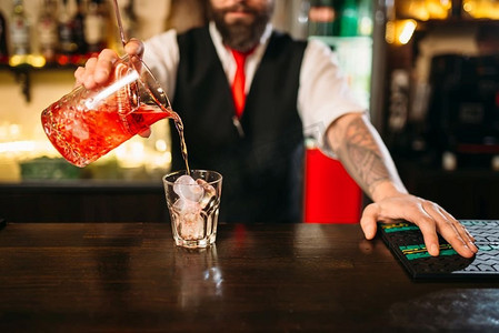 酒保倒酒精饮料在玻璃。餐厅里的调酒师。酒保倒酒精饮料在玻璃
