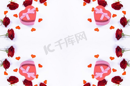 红色鲜花礼物摄影照片_情人节的心框，红玫瑰花朵和白色背景上孤立的礼盒。情人节礼物和鲜花