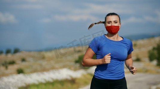 一名运动妇女带着防护面罩在乡村道路上跑步