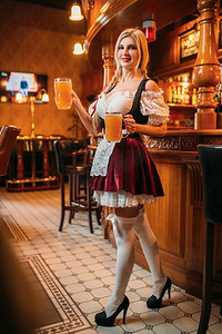 性感的女服务员复古制服举行两杯新鲜啤酒在酒吧。在传统风格的衣服中有吸引力的形状的Fasheberfest酒吧女招待