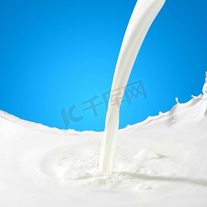 牛奶翻倒摄影照片_倒牛奶水花。在彩色背景上浇上白牛奶水花