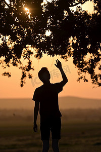 耶稣祈祷摄影照片_特写肖像年轻男子在日落时举手祈祷