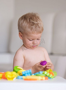 男婴玩和有乐趣与五颜六色的建模粘土（橡皮泥或面团）