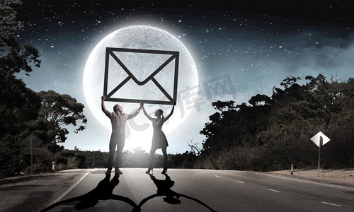 电子邮件概念。年轻夫妇剪影在晚上举行电子邮件标志