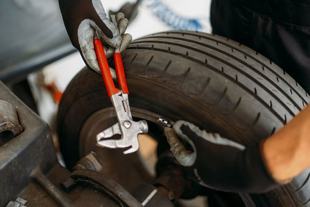 汽车机械平衡轮专用机，轮胎维修。男人在车库修理汽车轮胎，专业汽车检查在车间
