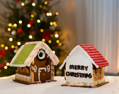 烹饪、假日和面包店概念—在圣诞树光背景的姜饼房子。圣诞树灯光下的姜饼屋