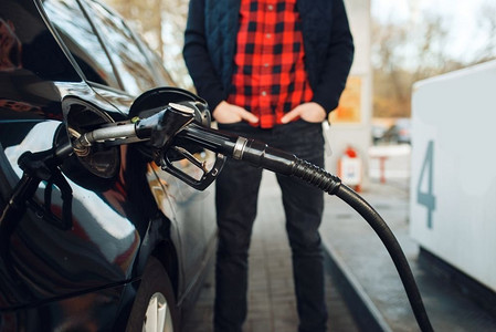 加油站加油，加油的人拿着枪加油车。汽油加油、汽油或柴油加油服务。加油站上有枪燃料车的男子