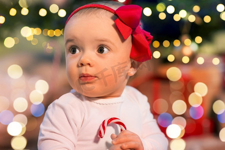 节日和童年的概念-圣诞树上的美丽女婴。圣诞树彩灯下的美丽女婴