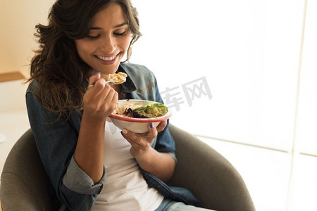抱着东西的女孩摄影照片_吃着一碗纯素食超级食品的女人