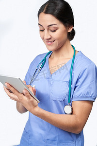工作室拍摄的女护士穿着磨砂膏使用数字平板电脑      