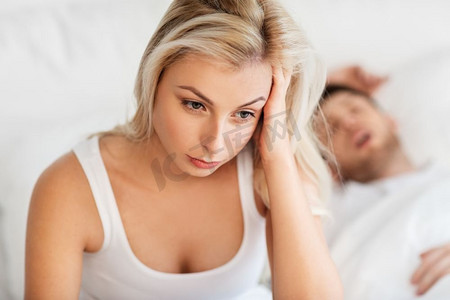 女人睡觉摄影照片_睡眠问题和人的概念—关闭躺在床上的不愉快的女人与打鼾的男人痛苦的不愉快的女人睡觉的男人